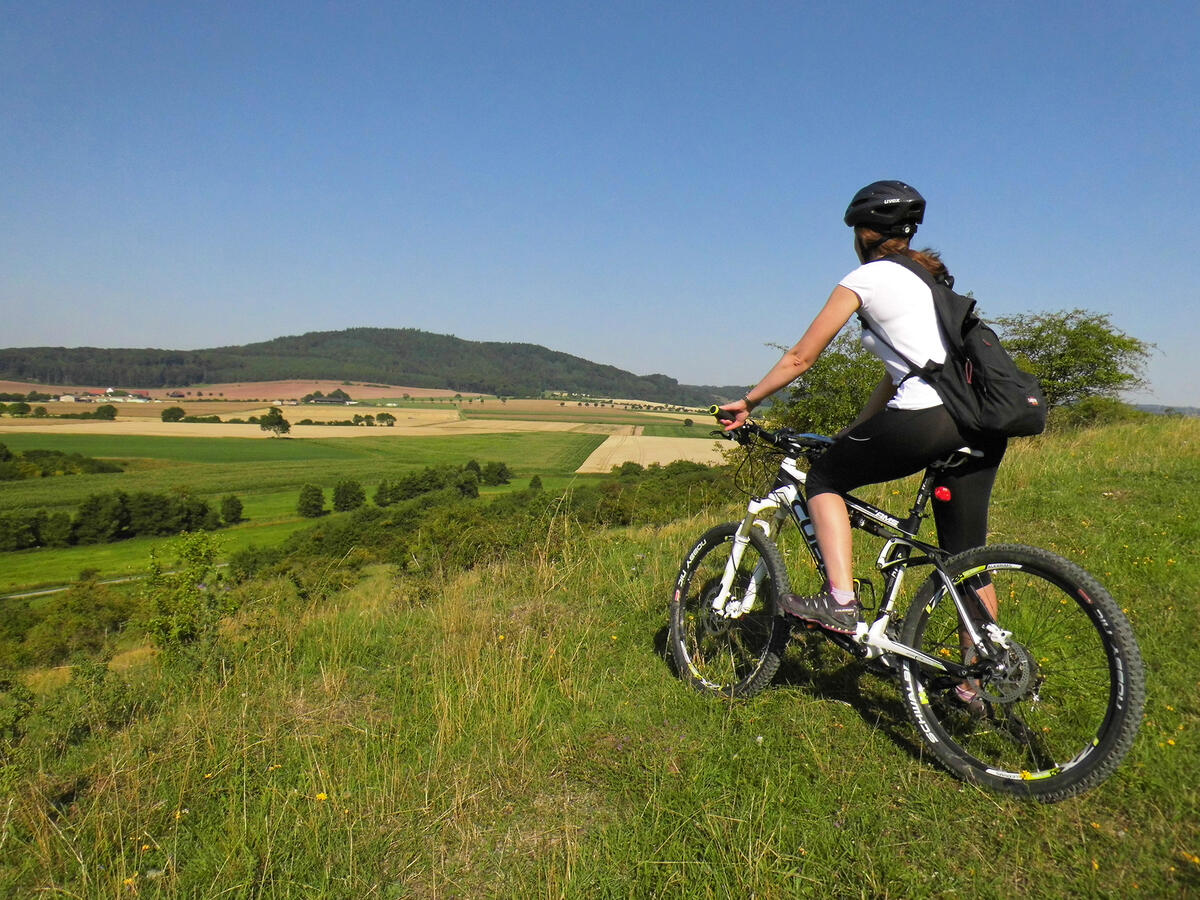 Eine Radfahrerin steht oberhalb der Marbeckhänge am Radweg KB1.