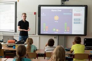 Bild vergrößern: Das Bild zeigt einen Lehrer und Schüler in einem Klassenraum.