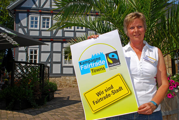 Bild vergrößern: Eine Frau mit Fair-Trade-Plakat steht vor dem Korbacher Weltladen