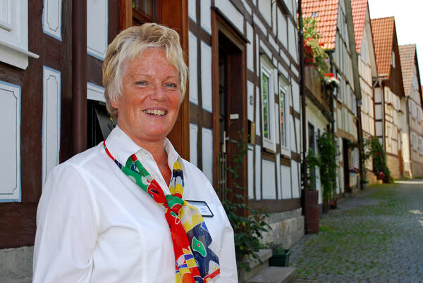 Bild vergrößern: Eine Frau steht vor der Fachwerkkulisse der Violinenstraße